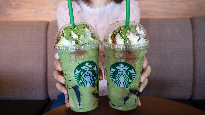 Customer holding two Starbucks green matcha Frappuccinos