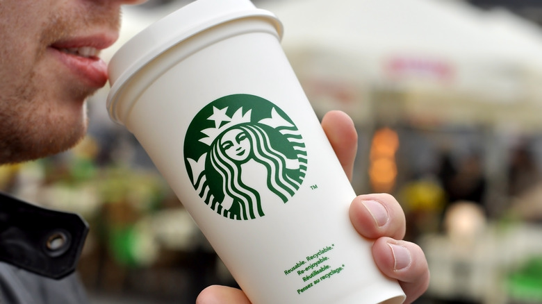 Person drinking from Starbucks cup